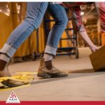 Image is about floor obstacles in the workplace slips trips and falls and warehouse safety depicting the legs and feet of a warehouse worker tripping and falling over yellow tape on the ground for A.R.M. action resource management