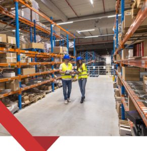 An image of a man and woman warehouse worker; the woman is showing the man where things are at the warehouse.