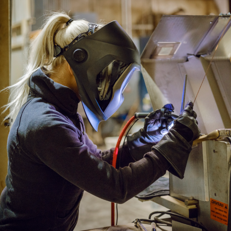 Woman welder wearing protective head gear as she works.