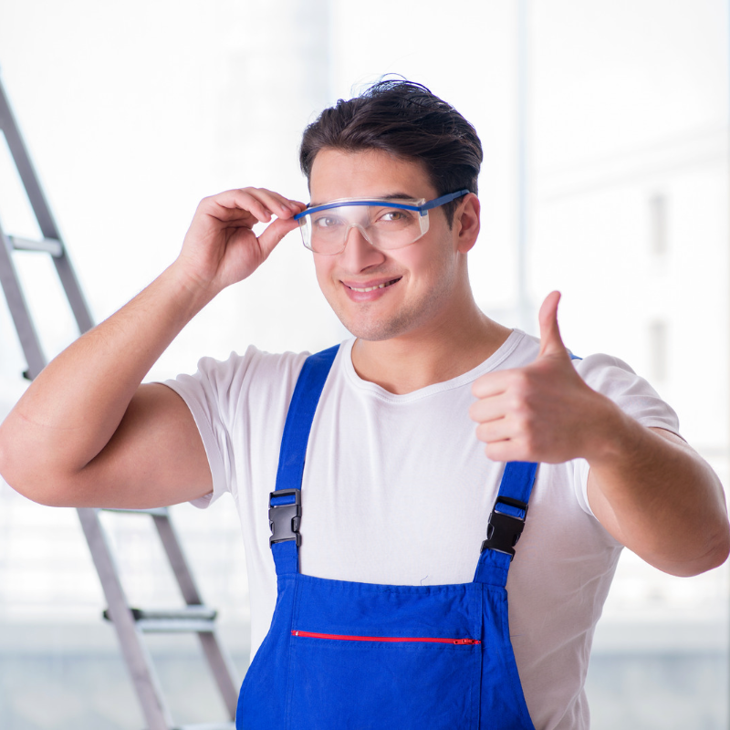 Image of brown-haired worker in blue overalls and white shirt wearing safety goggles with his thumb up eye safety A.R.M. action resource management