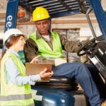 Image shows woman standing beside forklift giving directions to the driver. warehouse safety tips A.R.M. action resource management
