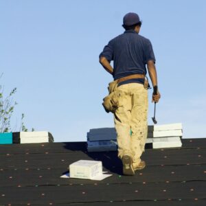 Image of roofer wearing safety gear and carrying hammer surveying the completed job A.R.M. action resource management