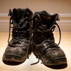 Close-up image of worn, old black work boots with loose laces for Safety on your feet A.R.M. action resource management