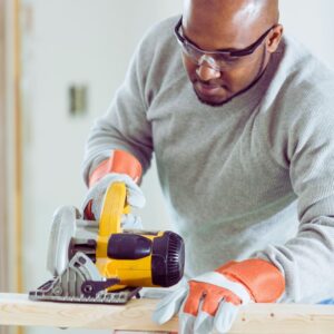 Image of a black man working with a sander at a work table wearing safety glasses and gloves A.R.M. action resource management Tool safety