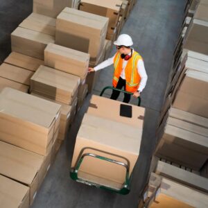 Image of warehouse worker pushing cart of boxes in narrow aisle. A.R.M. action resource management