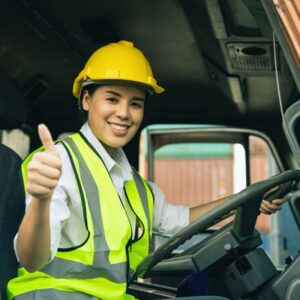 Young warehouse woman in yellow safety vest and hard hat gives thumbs-up from forklift A.R.M. action resource management