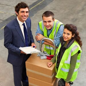 Image from above of warehouse boss in business suit and tie and two warehouse workers wearing bright yellow safety vests, one leaning on the truck. A.R.M. Action Resource Management