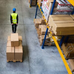 Image from above of warehouse worker wearing yellow safety vest and blue hard hat pulling a pallet lifter. A.R.M. Action Resource Management Safety training