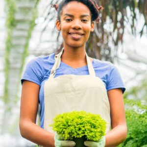 Image of smiling young woman worker holding a lettuce bunch, wearing an apron and gloves. Action Resource Management. A.R.M.