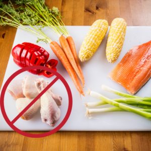 Image of fresh vegetables on a white cutting board, with raw chicken legs at the bottom. Prevent Foodborne Illness. Foodborne illness safety. A.R.M. Action Resource Management
