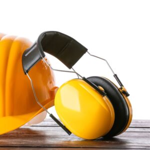 This image shows Personal Protective Equipment (PPE) with bright shiny yellow covers over the ear muff portion. The ear muffs are leaning against a yellow hardhat. A.R.M. Action Resource Management. OSHA safety training.
