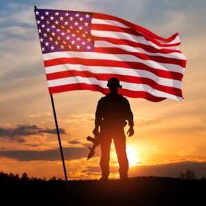 This image shows the silhouette of a soldier, with a sunset and large American flag behind him. A.R.M. action resource management. jobs for veterans.