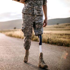 This image shows a soldier from the trunk to the feet. Their left leg is a prosthetic one, as their leg is amputated at the knee. Veterans Day. A.R.M. action resource management.