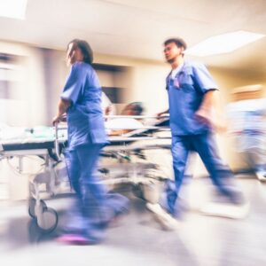 Blurry action image of emergency room workers running a sick or injured person on a gurney. A.R.M. Action Resource Management Safety training