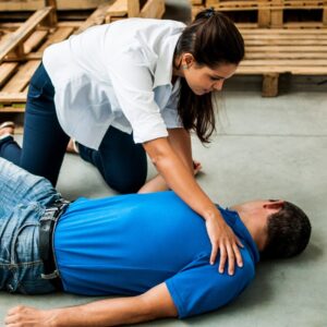 This image shows a woman warehouse worker helping another worker who is on their back, convulsing. A.R.M. Action Resource Management.