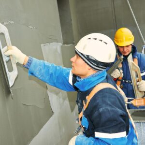 This image shows workers wearing jackets, gloves, scarves and hard hats, spreading drywall, Action Resource Management A.R.M.