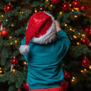 An image of a child placing a decoration on the Christmas tree. ARM