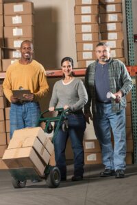 A group of three warehouse workers, two men and a woman. ARM