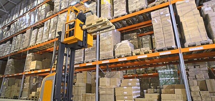 An image of a warehouse worker using a cherry picker forklift at work. Forklift - Cherry/Picker Operator