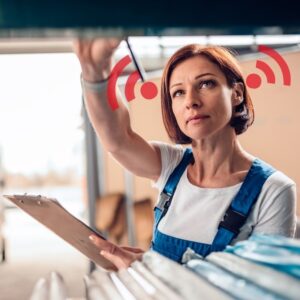 An image of a warehouse clerk wearing blue overalls with a short sleeved white shirt beneath. There are noise graphics at her ears, indicating that she is in a loud environment. Hearing loss.