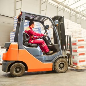 An image of a forklift driver driving in the warehouse with a load.