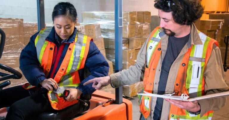 Building a Safety Culture in the Workplace. An image of a warehouse manager teaching a new worker safety techniques on the forklift.