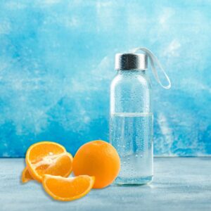 A clear water bottle with a whole orange and orange slices.