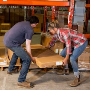 warehouse workers lifting a box together properly