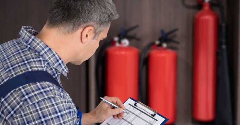 Tech inspecting fire safety equipment at warehouse. Ready for Anything: Fire Prevention in Industrial Workplaces